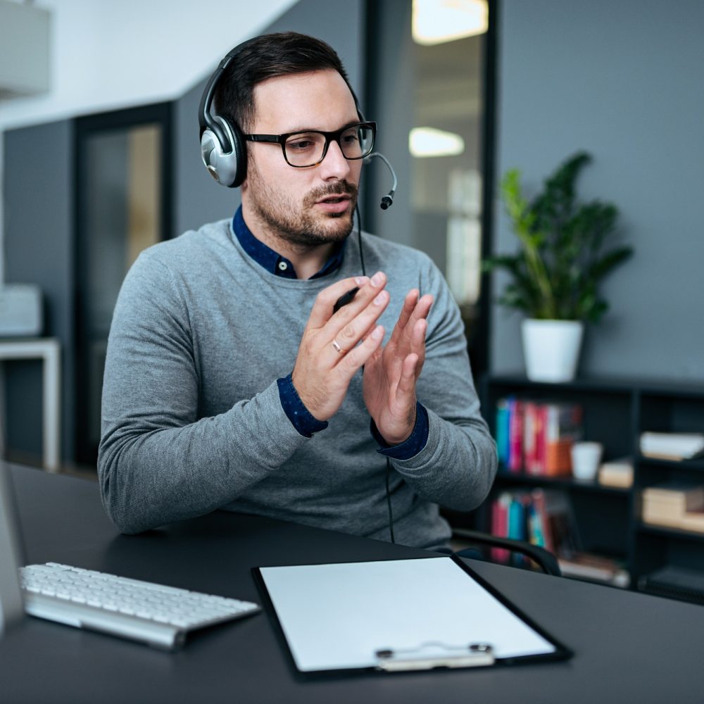 Young handsome male customer support phone operator with headset working in his office.