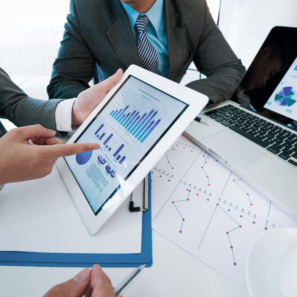 Group of executives discussing business activity graphs on tablet screen